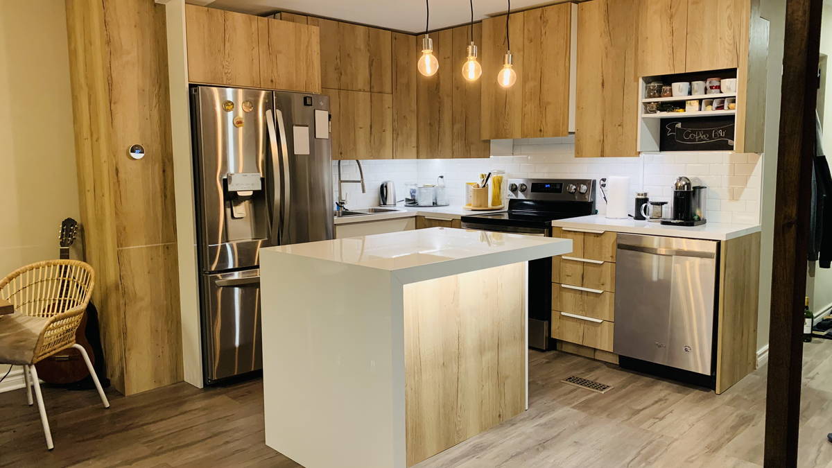 Modern residential kitchen with wood cabinets, white island, and stainless steel appliances.